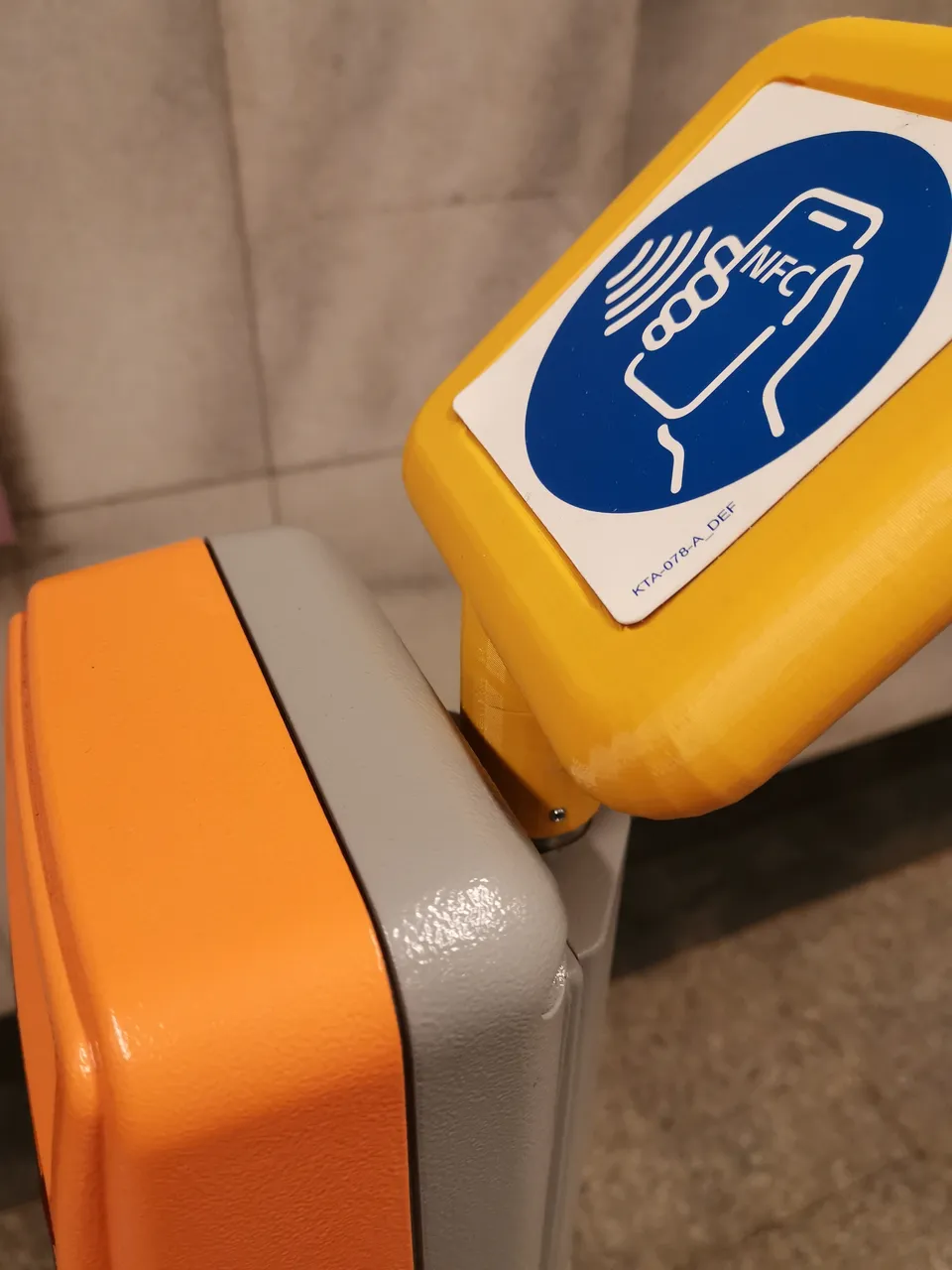 3D nyomtatott sárga NFC-foglalat közelről a BKK metró jegyérvényesítőjén